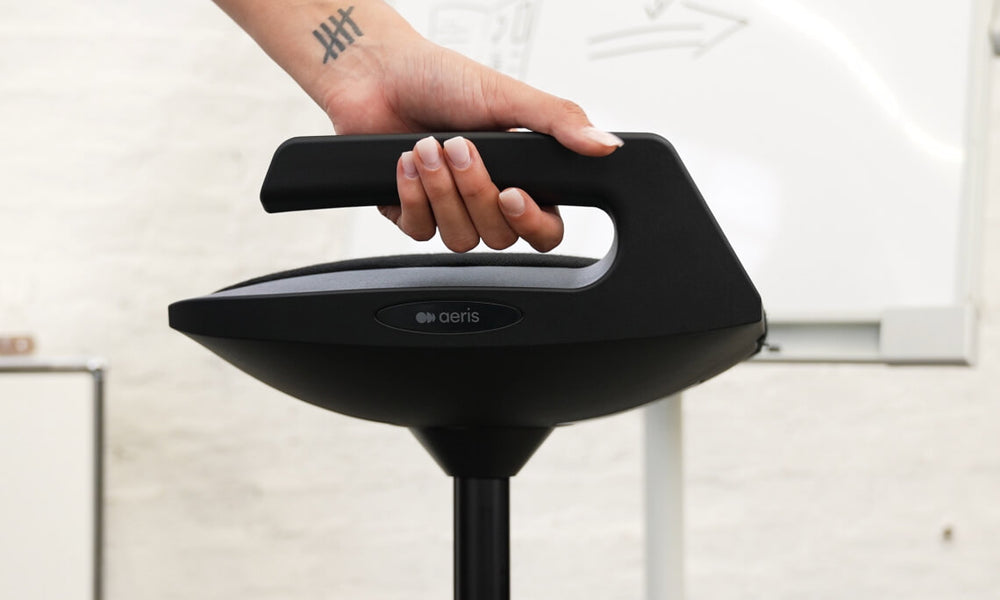 Image detail of Aeris Muvman seat. It shows a female hand holding the integrated handle in order to carry it. 