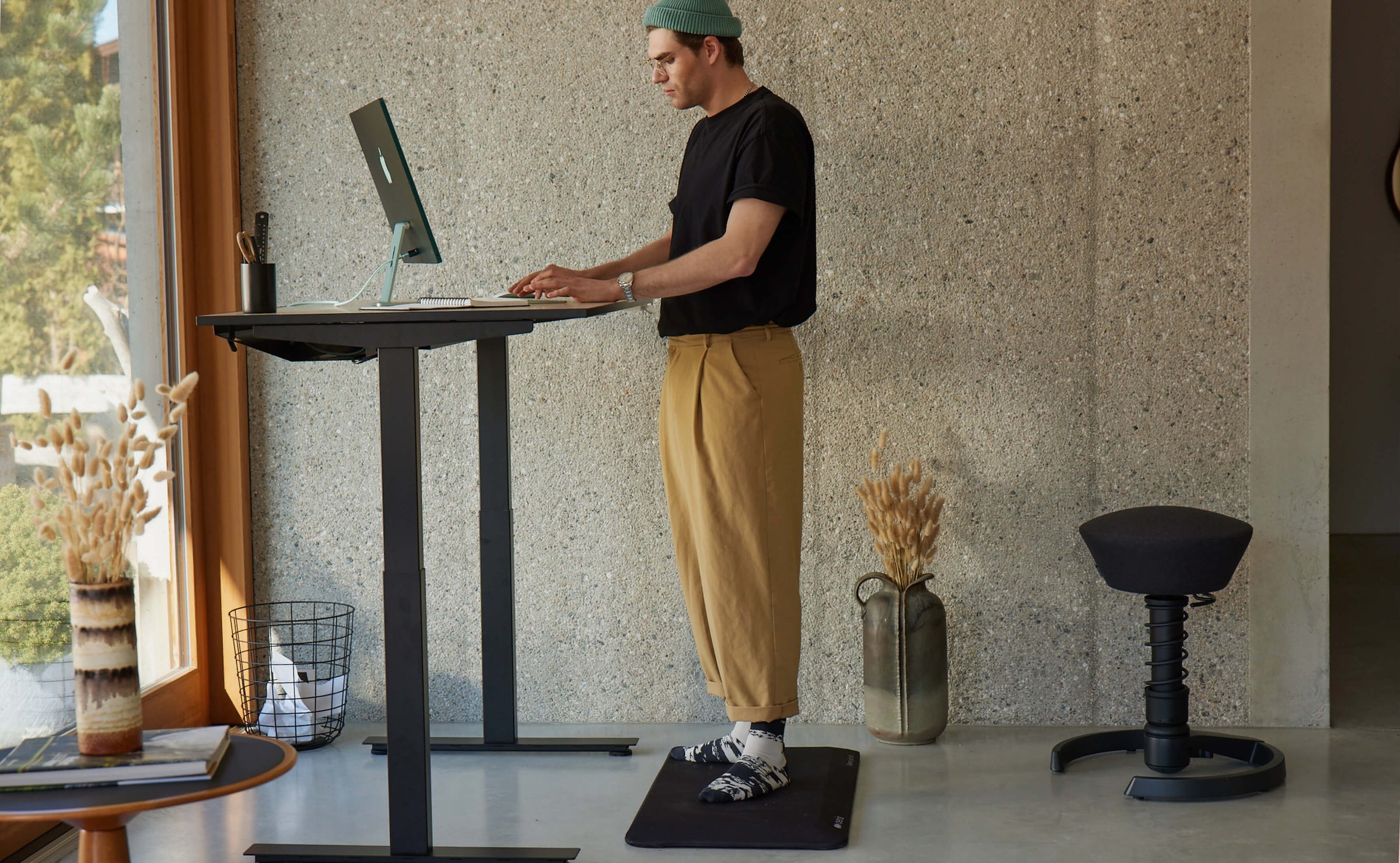 A guy working on standing mat Aeris Muvmat at a height adjustable desk.