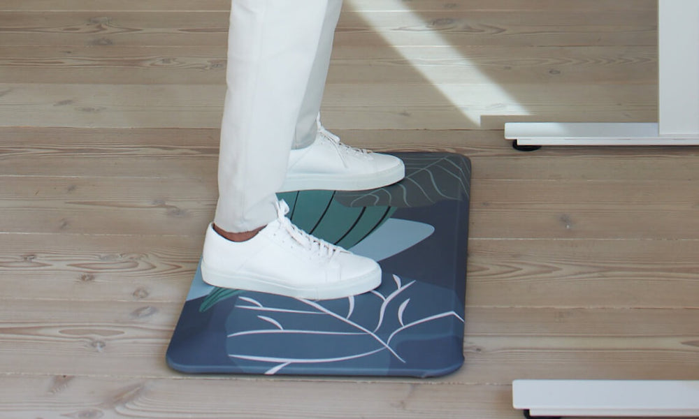 Image detail of a man's feet standing safely on the Aeris Muvmat standing mat with jungle design cover.