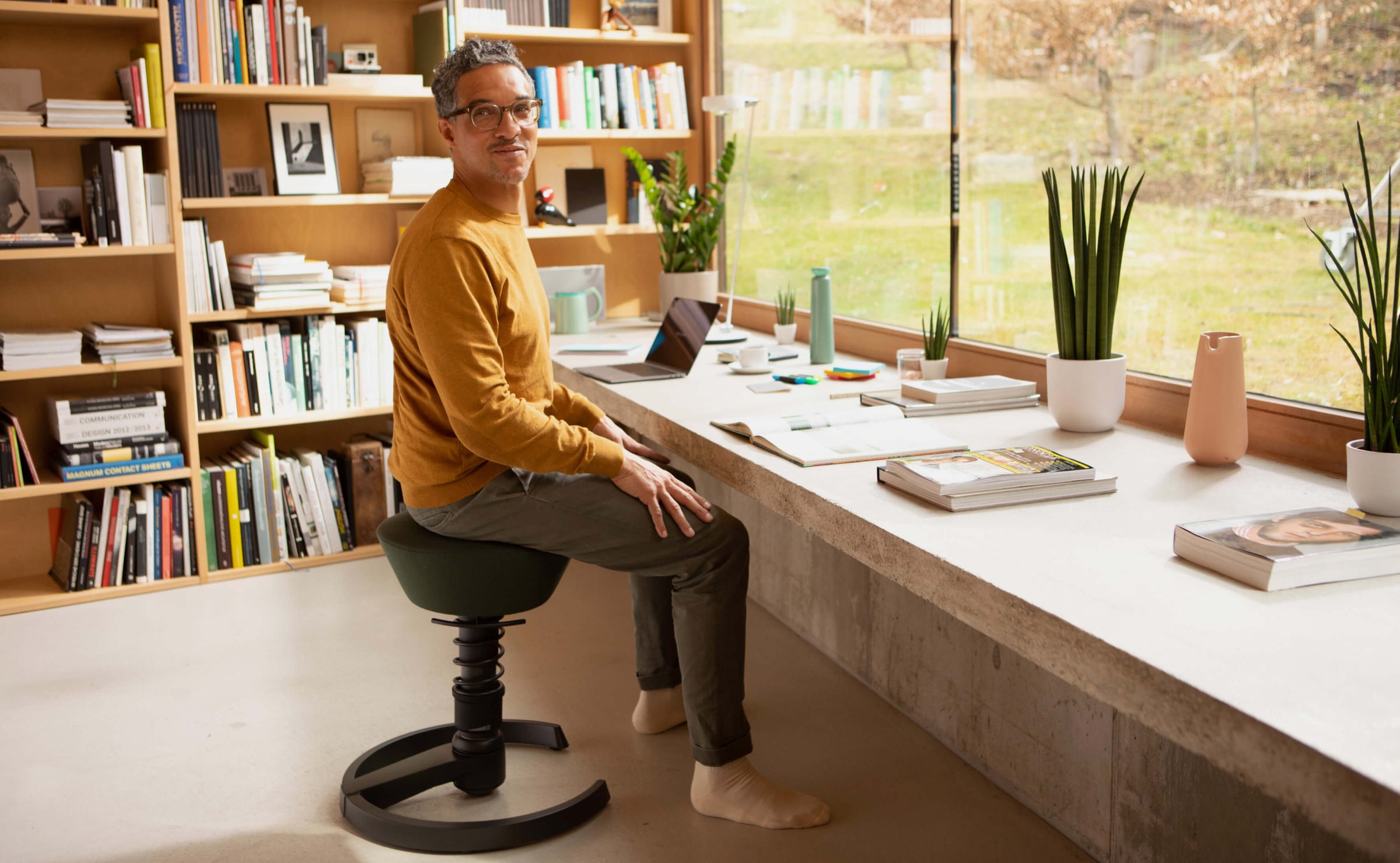 A man sitting on Aeris Swopper in an upright posture in his study room.