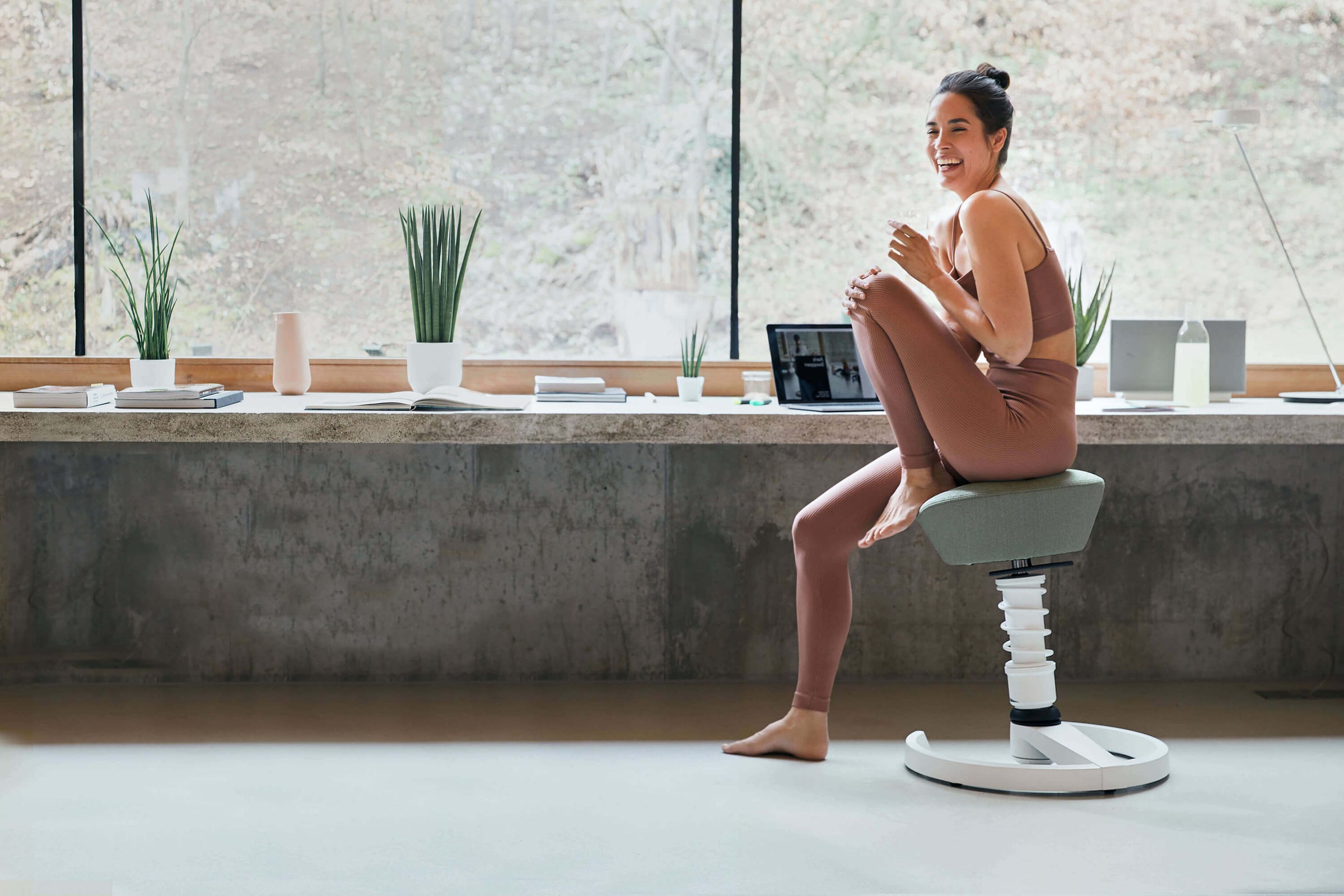 A woman sitting on a grey Aeris Swopper while working from home.